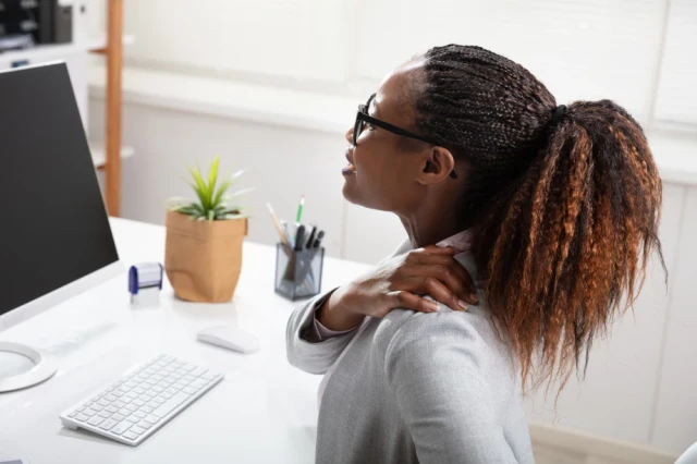 Woman sitting in front of computer with shoulder pain