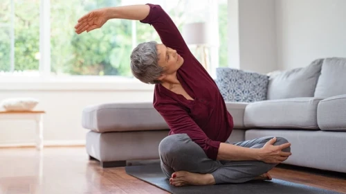 Mature Woman Stretching on Yoga Mat in Living Room