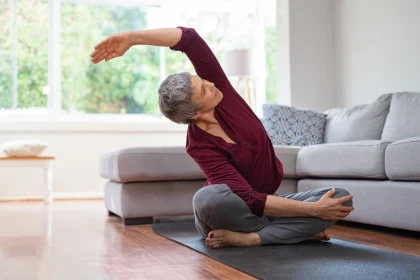 Mature Woman Stretching on Yoga Mat in Living Room