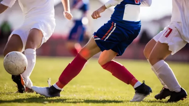 Men playing soccer in field