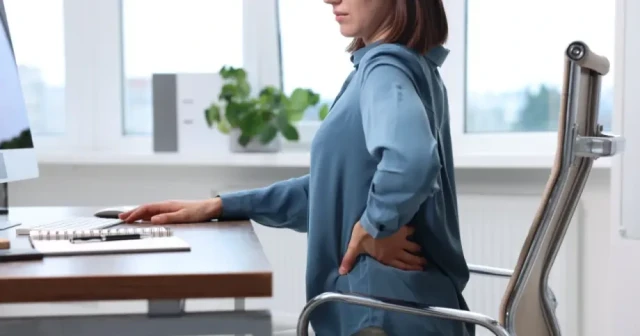 woman touching back and appearing in pain